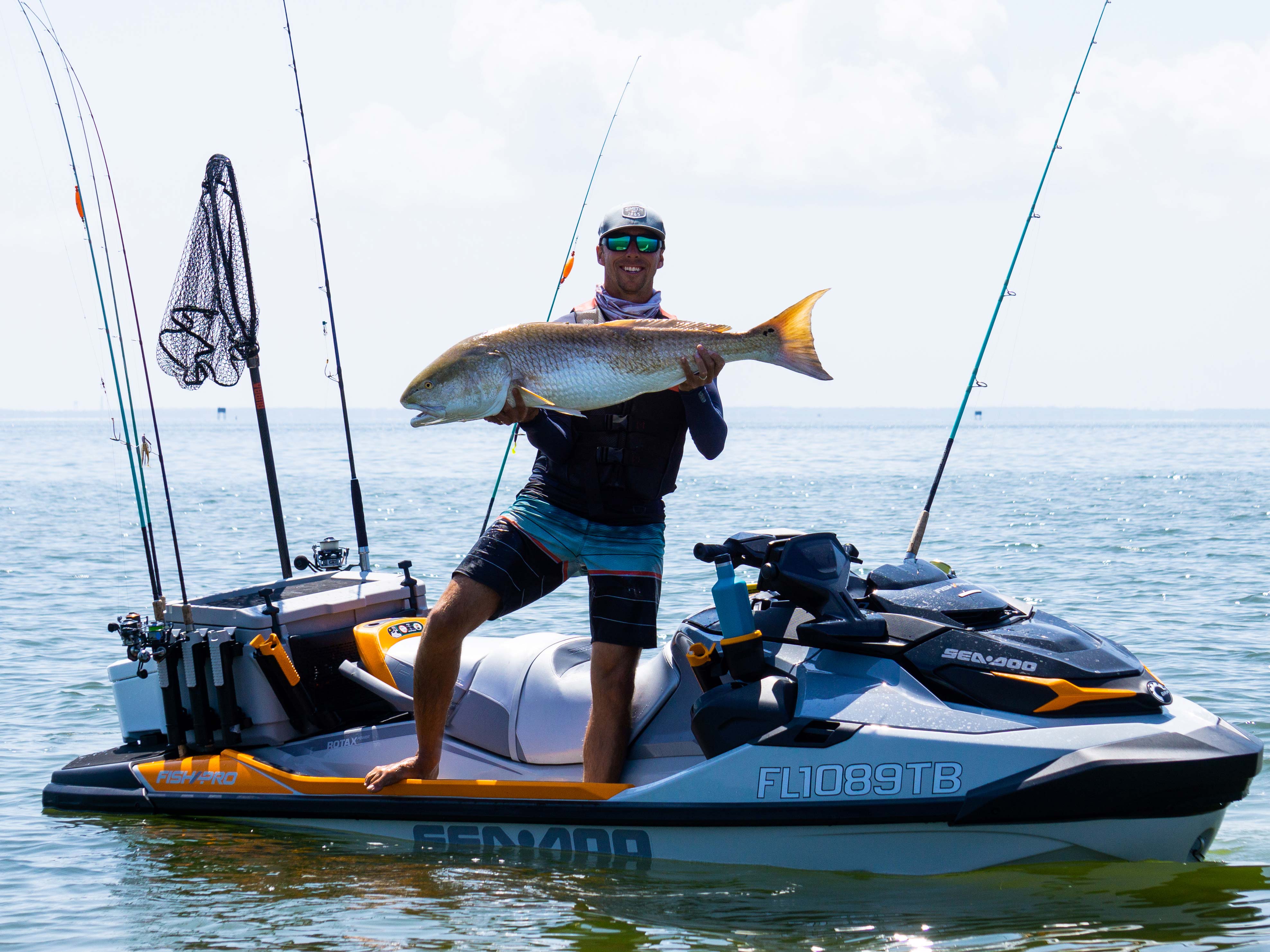 Brett Barley holding a fish next on his Sea-Doo GTI-SE