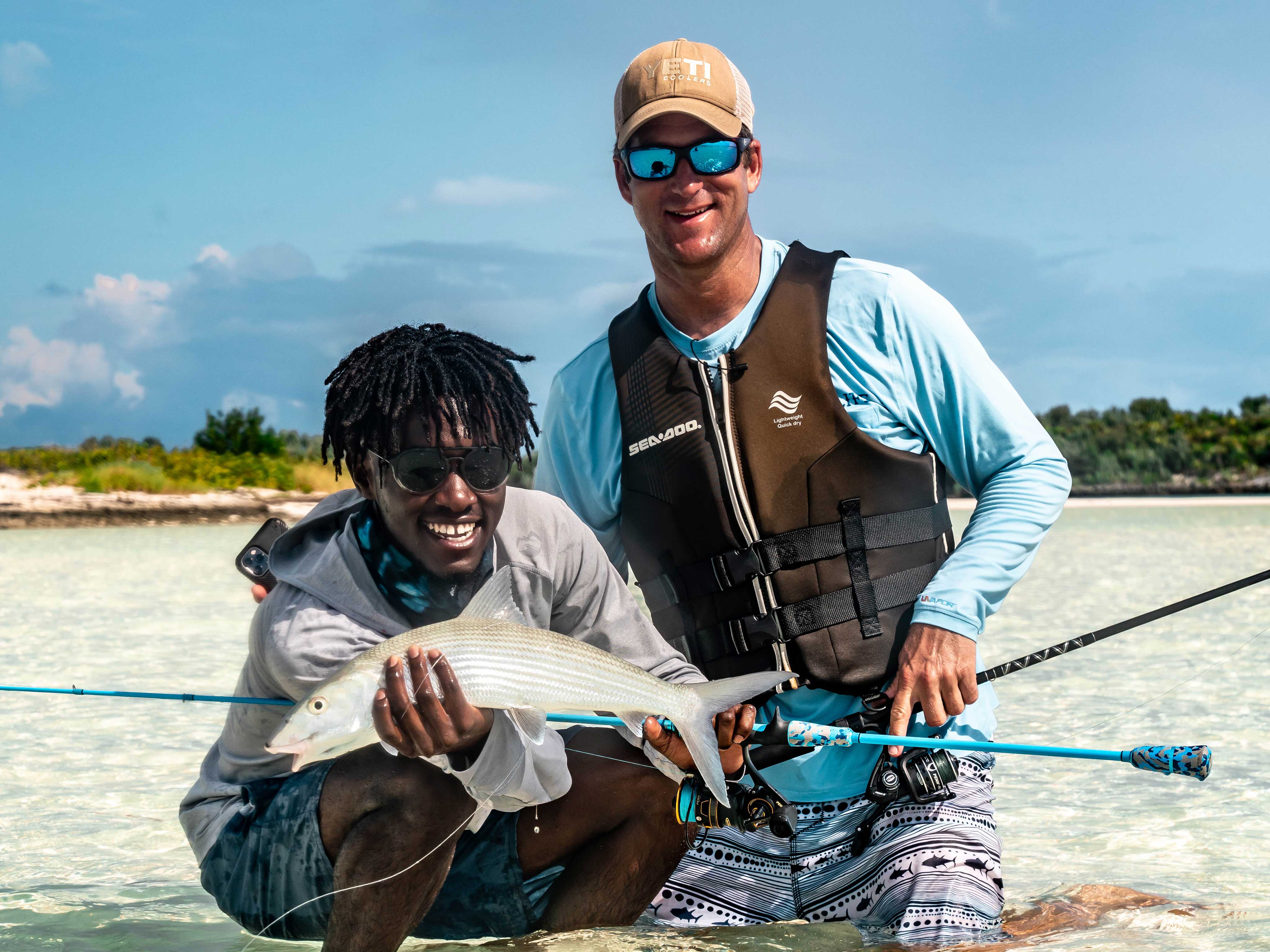 Two happy men holding fish next to Sea-Doo