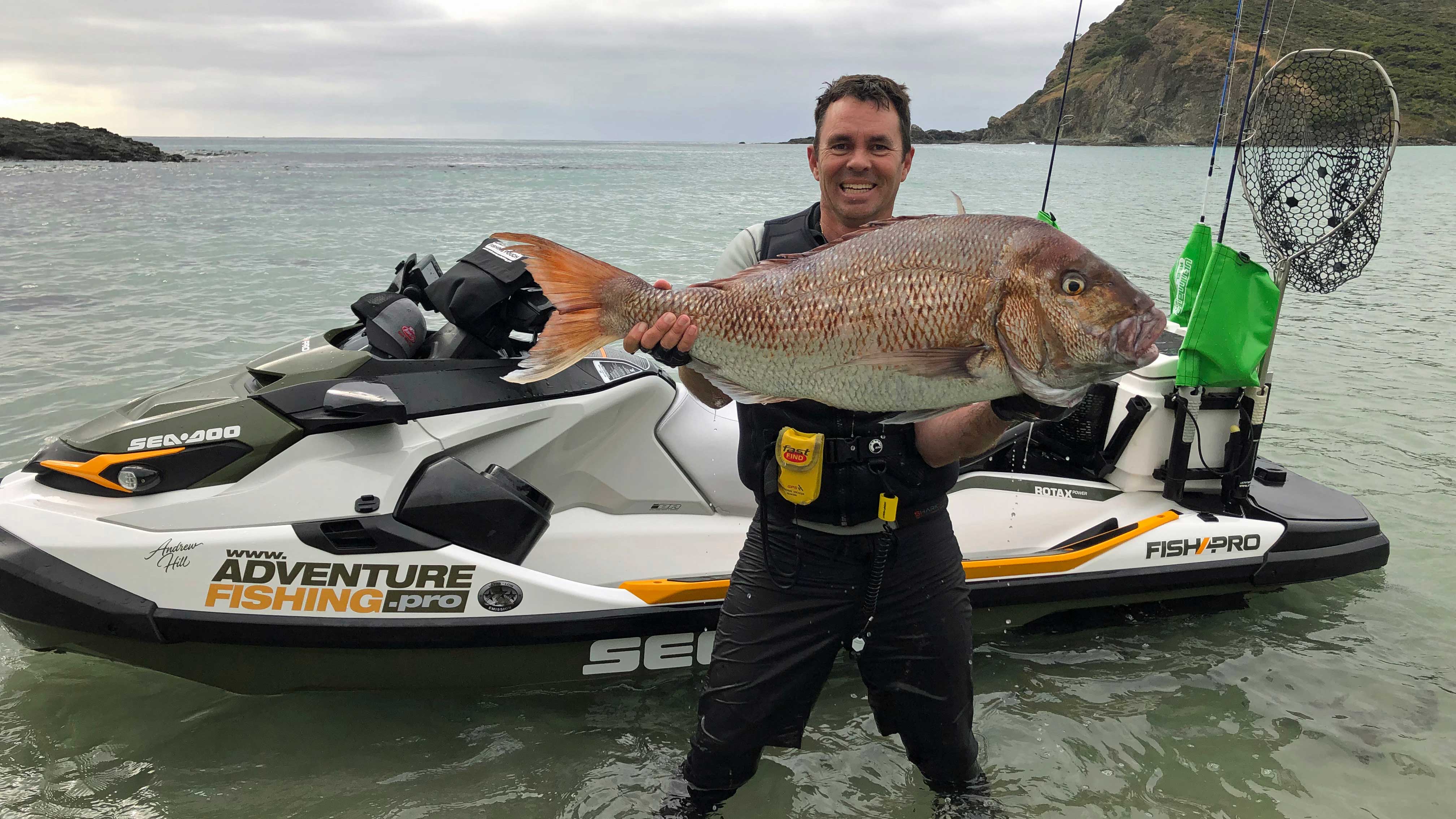Andrew Hill holding a fish next to his Sea-Doo FishPro