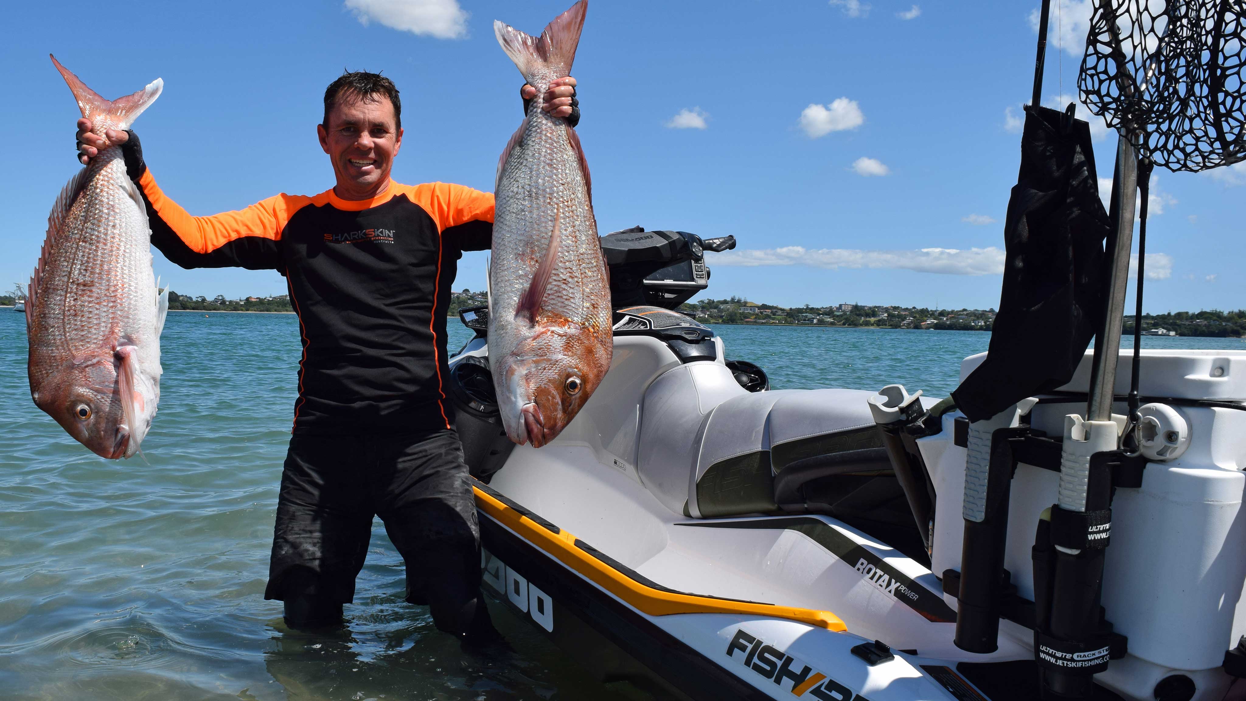 Andrew Hill holding two fishes next to his Sea-Doo FishPro