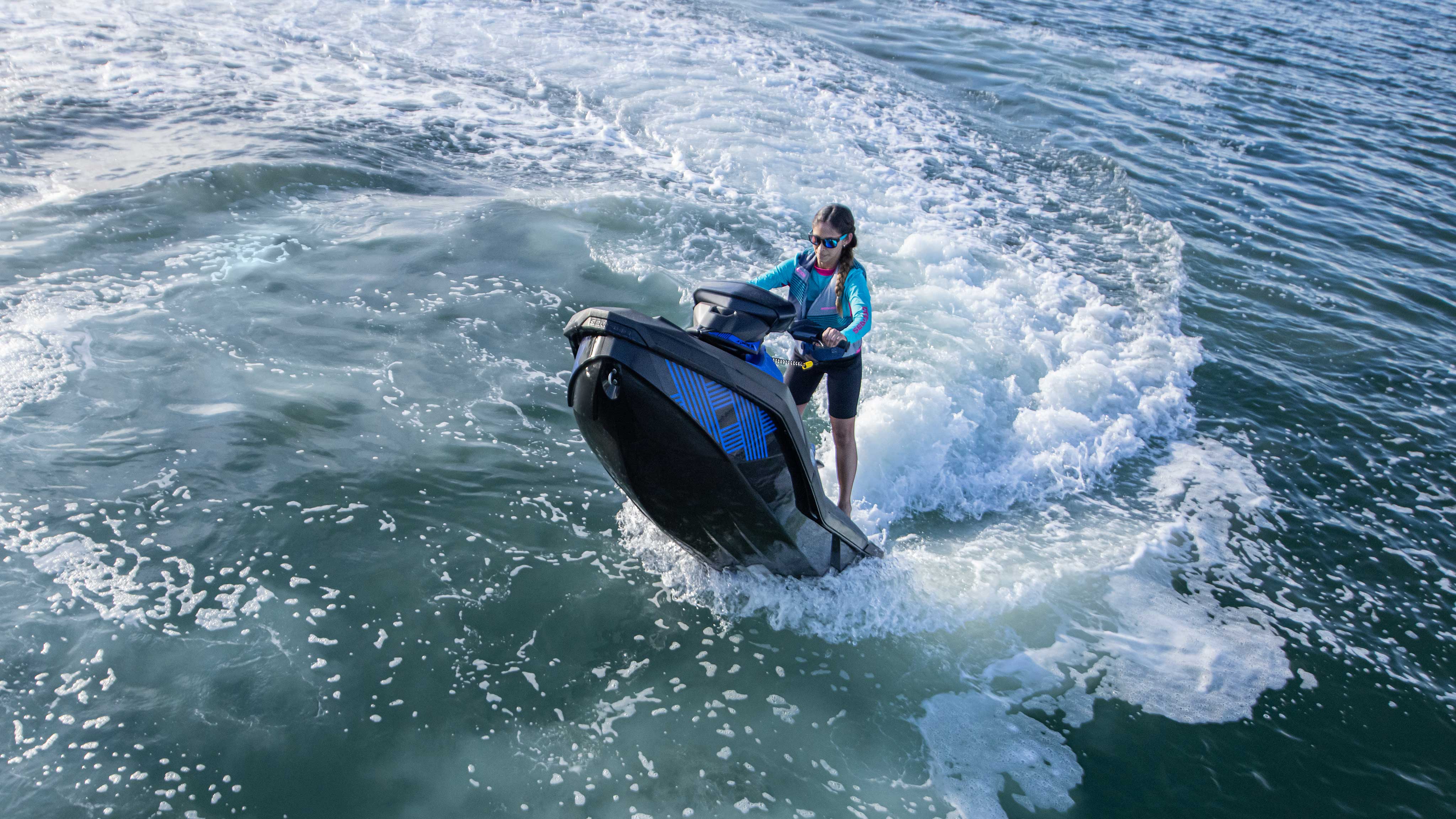 Vrouw doet een wheelie op haar blauwe Sea-Doo Spark Trixx