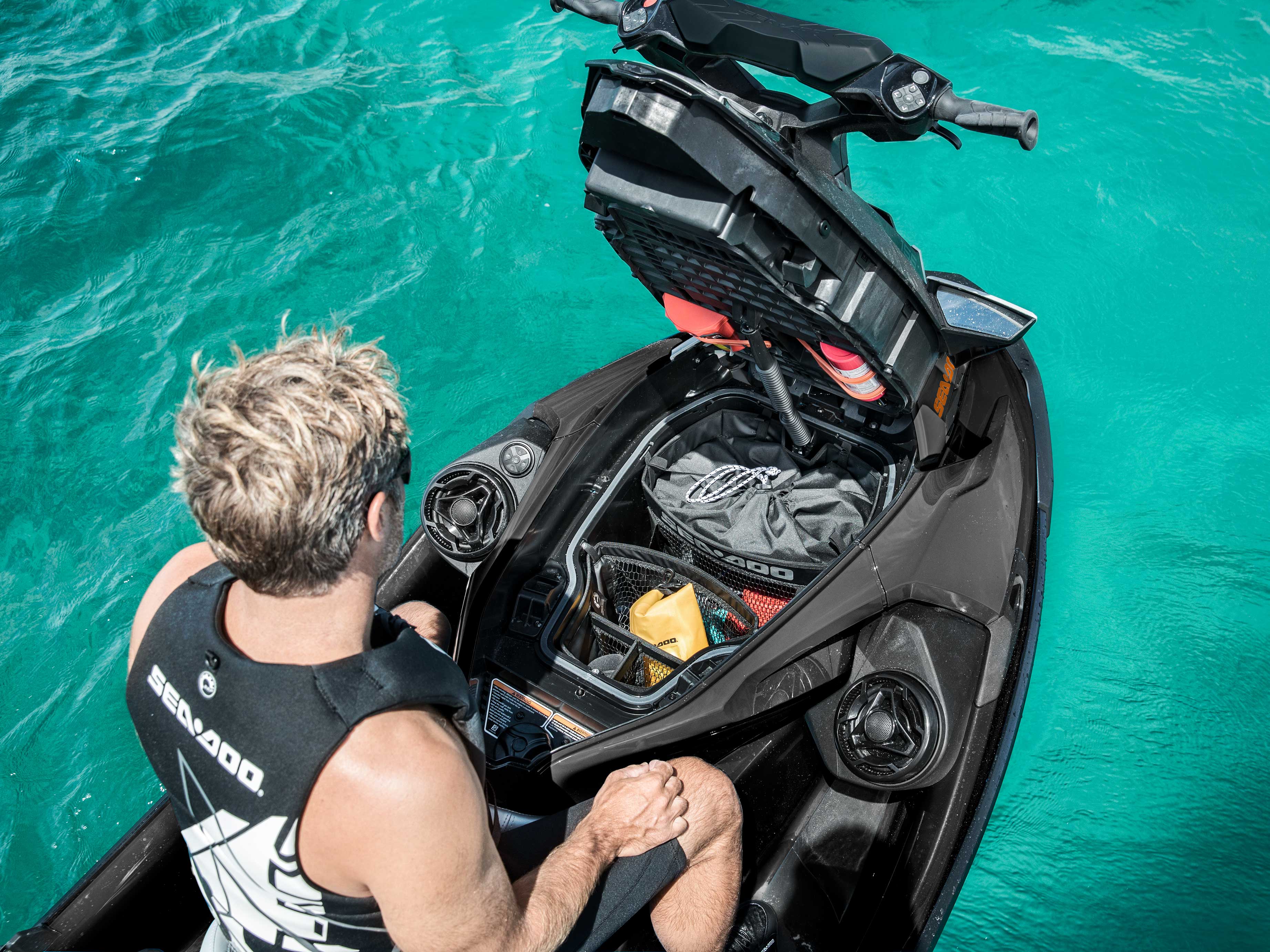 Overhead image of a person on a Sea-Doo floating on water with the front storage opened and audio system installed