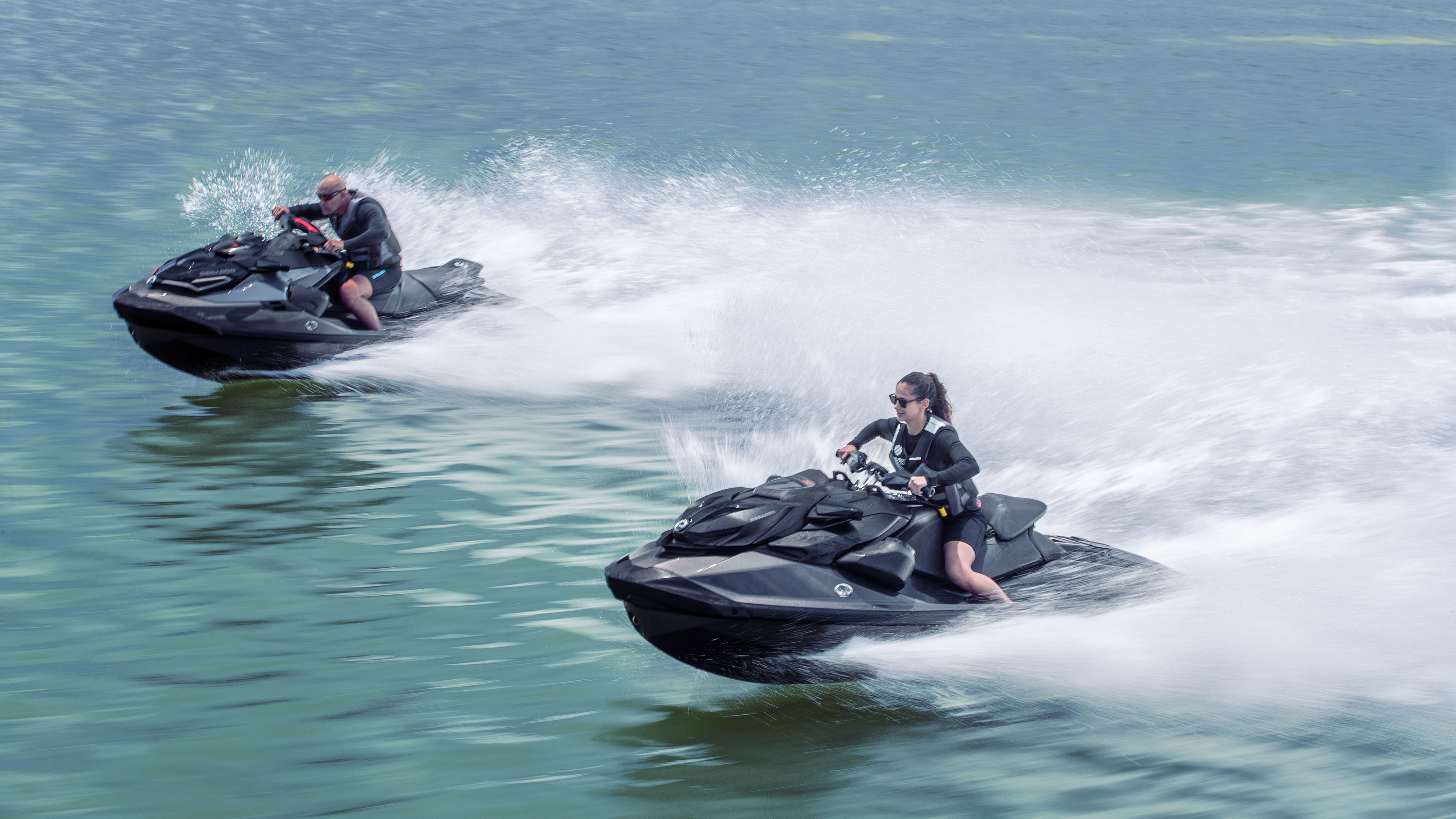 Un hombre y una mujer a toda velocidad con las motos acuáticas personales Sea-Doo Performance