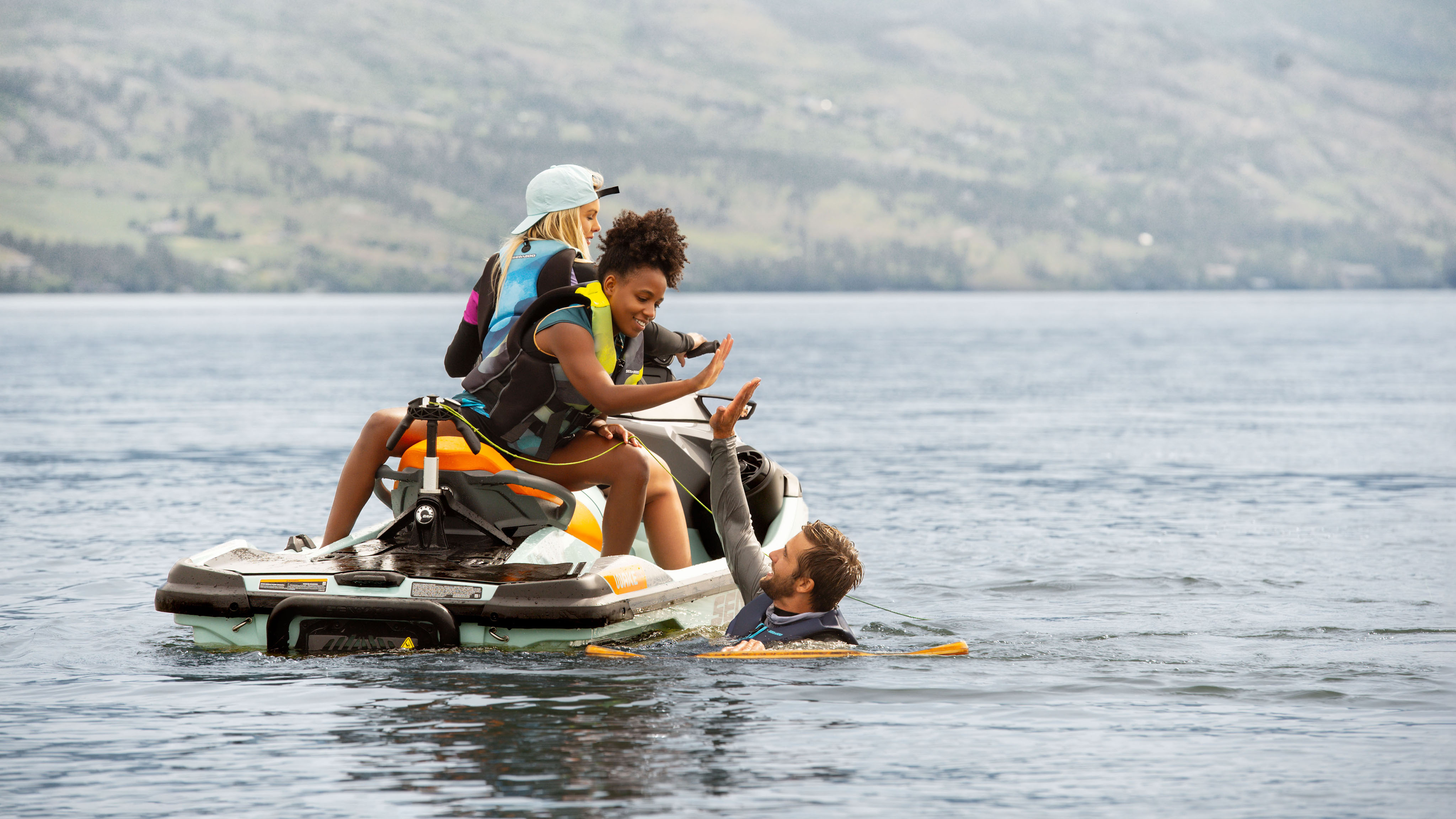 Hombres en el agua chocando los cinco con su amigo en una Sea-Doo Wake Pro