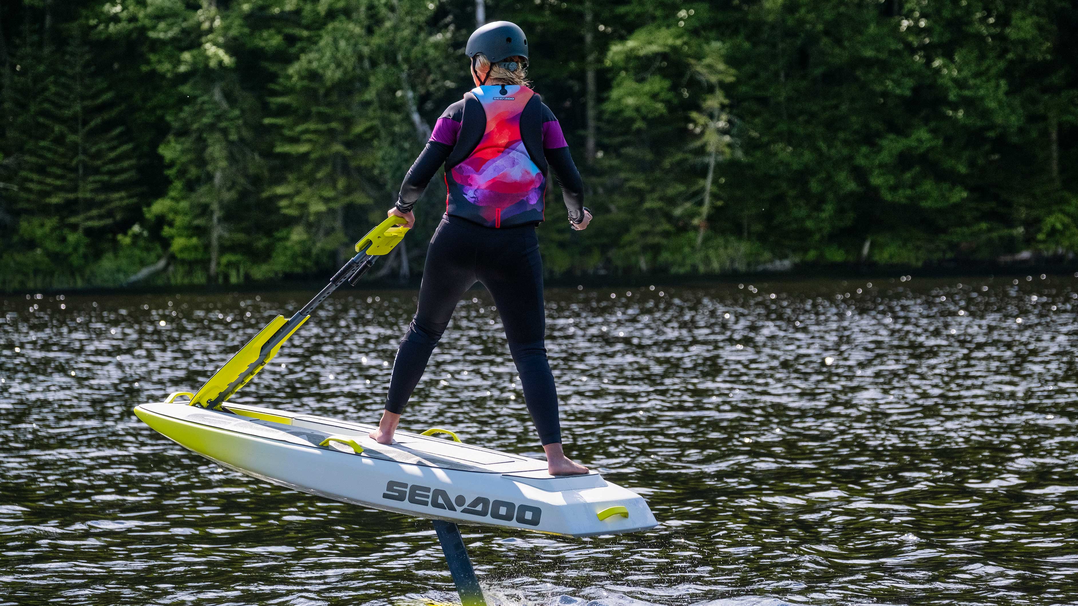 Femme surfant avec le Sea-Doo Rise, nouvelle planche de surf électrique à foil volante