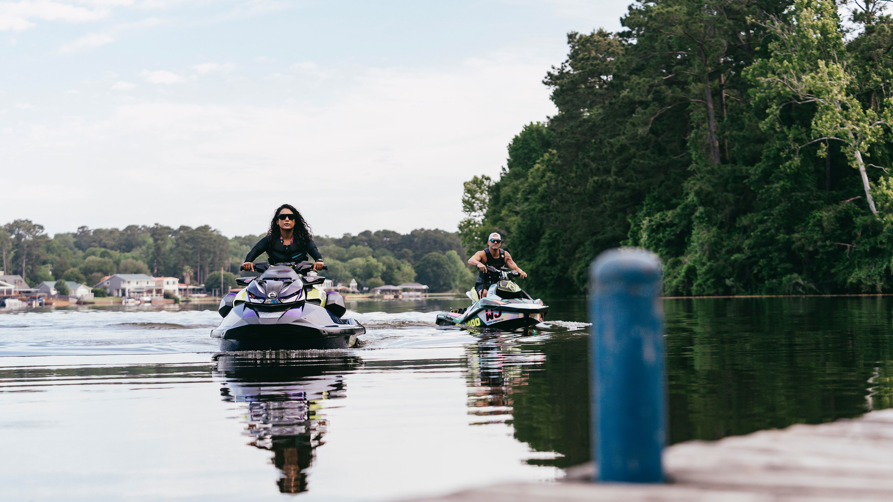 Two Sea-Doo riders riding slowly close to a dock